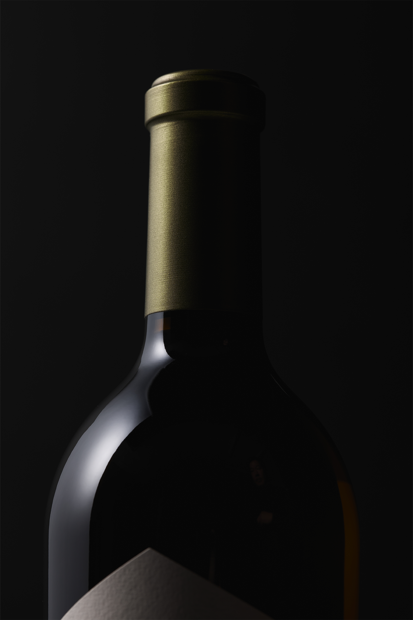 A close-up of a 2023 Estate Sauvignon Blanc wine bottle with a metallic gold foil cap, partially illuminated against a dark background. The Howell Mountain Estate label is only partially visible at the bottom.